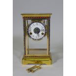 A polished brass four glass mantel clock with inset cloisonne panels, enamel dial and French