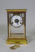 A polished brass four glass mantel clock with inset cloisonne panels, enamel dial and French