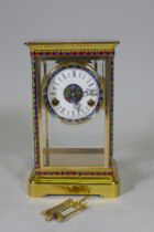 A polished brass four glass mantel clock with inset cloisonne panels, enamel dial and French