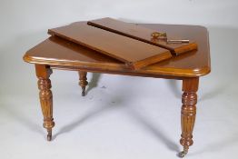 A Victorian mahogany wind out dining table with two extra leaves, raised on turned and fluted