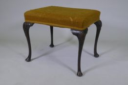 A Georgian style oak footstool, raised on cabriole supports with carved palm and harebell
