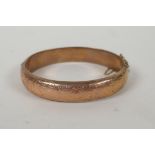A 9ct gold bangle with scrolling decoration and inscription, 6 x 5.5cm, 14.9g