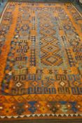A large Middle Eastern orange and burgundy ground hand woven kilim carpet, 310 x 500cm