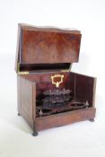 A C19th amboyna and ebony serpentine front decanter case, the lift up top and fold out sides opening