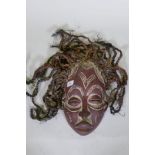 An African tribal carved and painted wood mask with braided straw decoration