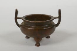 A Chinese bronze two handled censer raised on tripod supports, Xuan character mark to base, 5cm