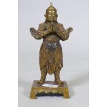 A Chinese bronze figure of a warrior god, hands clasped in prayer, impressed seal mark verso, 23cm