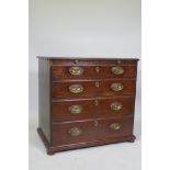 A Georgian mahogany chest of four long drawers under a brushing slide, raised on later bun feet