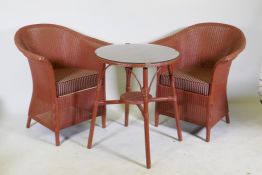 A Lloyd Loom occasional table with glass top and two armchairs, 60cm diameter