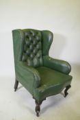 An early C20th button back leather wing armchair, raised on cabriole supports
