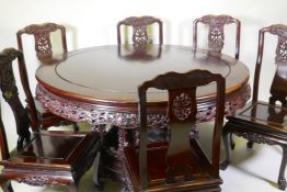 A Chinese rosewood dining table, with carved and pierced frieze, raised on a carved base decorated