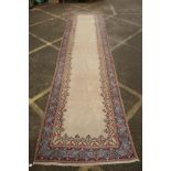 An Oriental cream ground hand woven wool runner with blue border and floral designs, 150 x 600cm