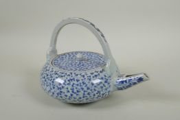 An early C20th Japanese blue and white porcelain tea pot of squat form, with all over scrolling vine