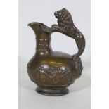 An antique cast bronze pitcher, with raised Bacchanalian decoration and lion handle, 23cm high