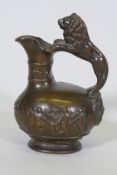 An antique cast bronze pitcher, with raised Bacchanalian decoration and lion handle, 23cm high