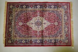 A red ground Kashmir rug with traditional floral medallion design and blue borders, 170 x 120cm