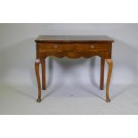 A Georgian style walnut two drawer writing table, with cross banded top, raised on cabriole