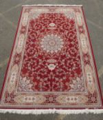 A fine woven full pile rich red ground Qom carpet, with floral medallion design and floral