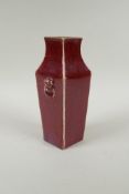 An antique porcelain sang de boeuf vase with twin mask handles, 20cm high