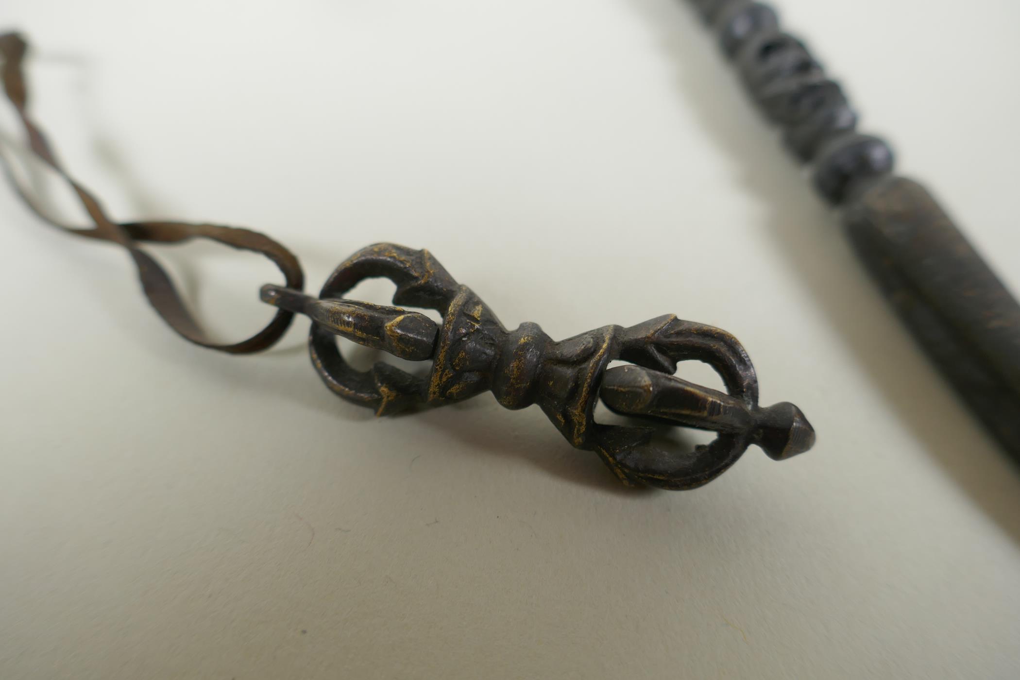 A Tibetan steel phurba with skull mask decorated to the handle and a miniature bronze vajra, 14cm - Image 2 of 3