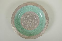 A Chinese celadon and silver glazed porcelain dish with raised dragon and lotus flower decoration,