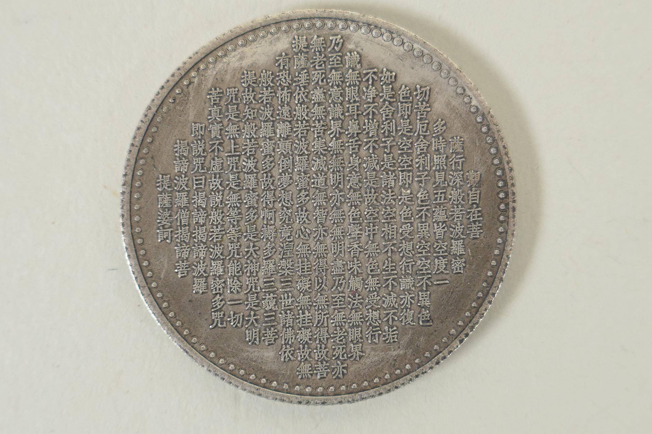 A Tibetan white metal token decorated with a tanka depiction and character inscription verso, 4cm - Image 2 of 2