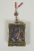 A Tibetan carved and painted hardstone tablet depicting a deity, the reverse set with abalone, dzi