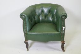 An early C20th button back leather tub chair with brass stud detail, raised on shaped supports