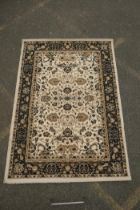 A Belgian cream ground rug with Oriental allover floral design and black borders, 150 x 212cm