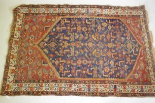 An antique Persian hand woven wool carpet, with medallion design on a red and blue field with