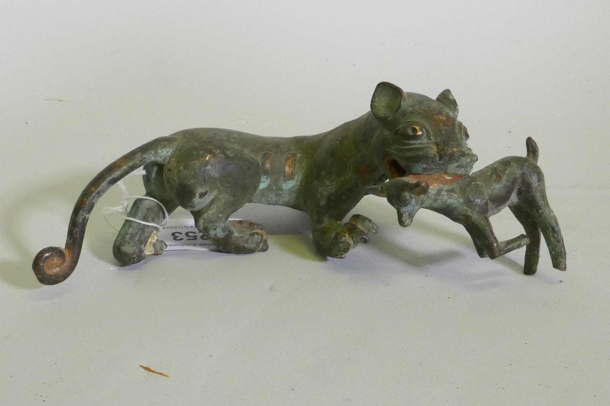 An Eastern bronze figure of a lion with prey, 20 x 7cm high