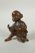 An Oriental bronze figure of a child practising martial arts, 9cm high