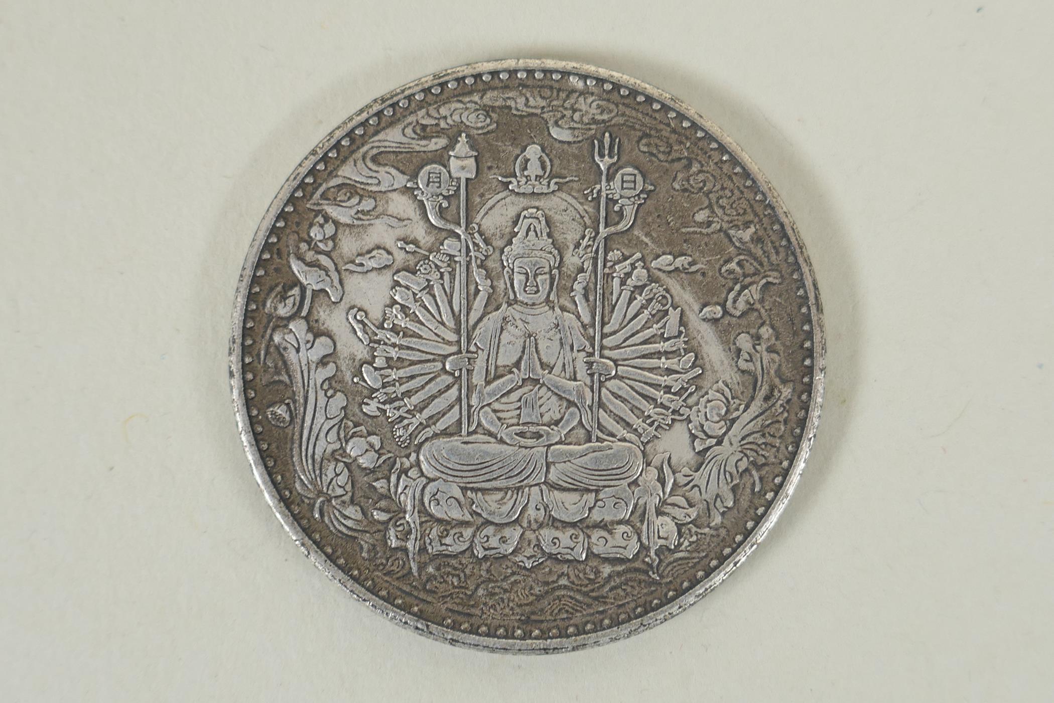 A Tibetan white metal token decorated with a tanka depiction and character inscription verso, 4cm