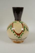 An antique Islamic earthenware vase with cream glazed body and treacle glazed neck, 25cm high