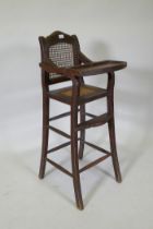 An oriental hardwood child's highchair with can back and seat, 103cm high