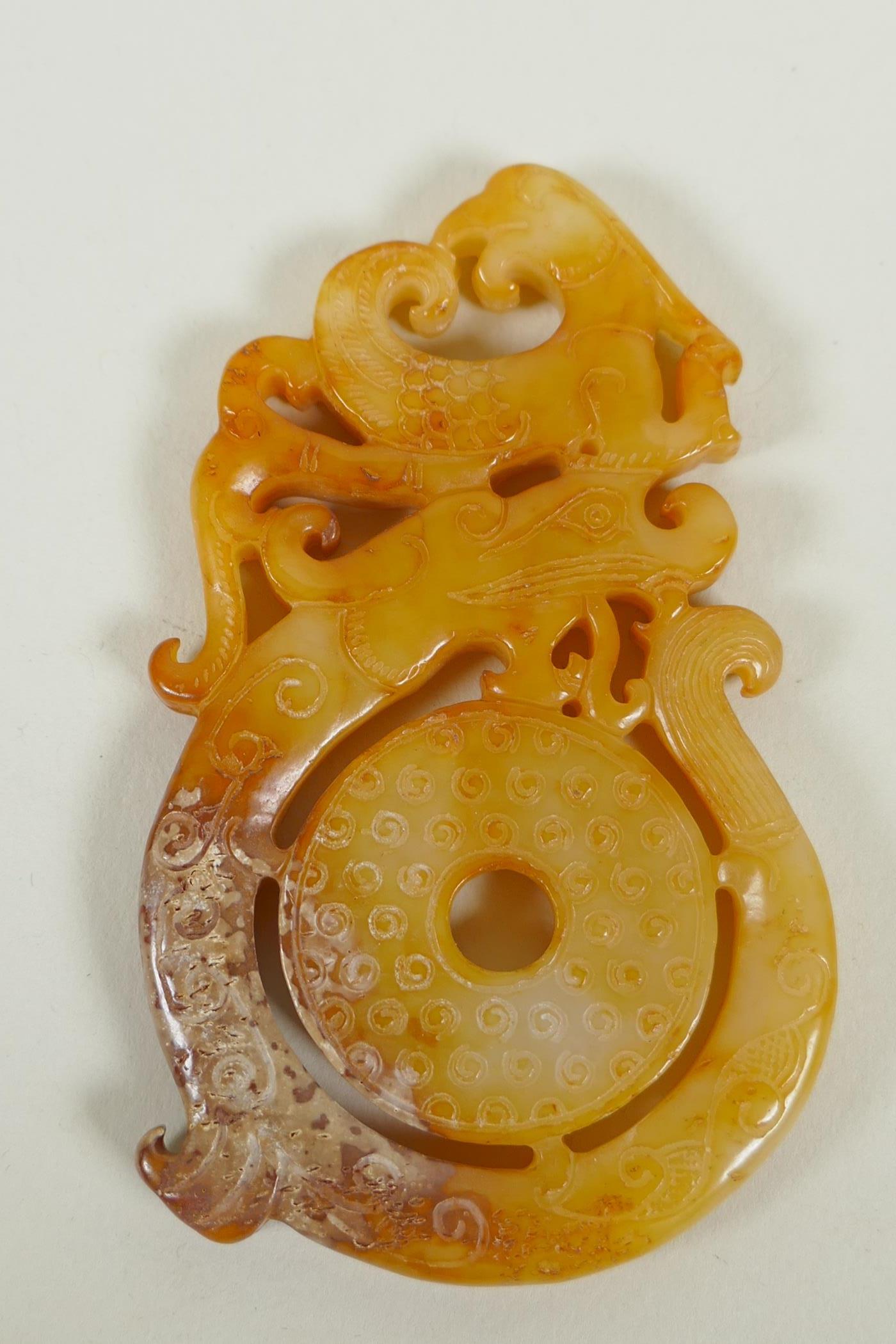 A Chinese archaic style carved jade pendant with stylised dragon and phoenix decoration, 9 x 5cm