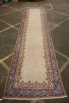 An Oriental cream ground hand woven wool runner with blue border and floral designs, 150 x 600cm