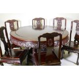 A Chinese rosewood dining table, with carved and pierced frieze, raised on a carved base decorated