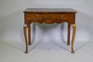 A Georgian style walnut two drawer writing table, with cross banded top, raised on cabriole