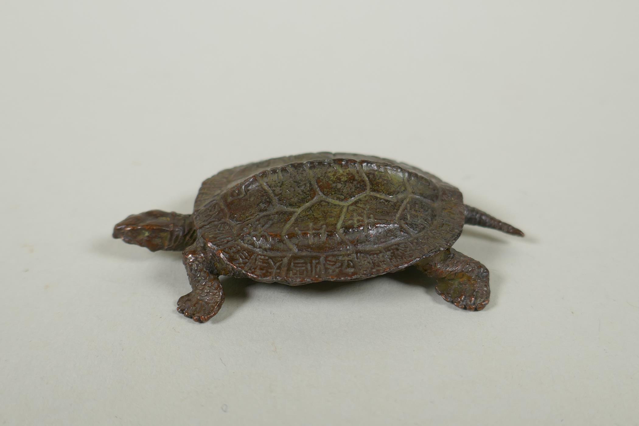 A Japane4se style bronze okimono tortoise, the shell with character inscriptions, 7cm long