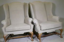 A good pair of Georgian style high back wing armchairs with wide seats, raised on walnut cabriole