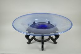 A large Murano blue glass charger, on an associated Chinese hardwood stand, 63cm diameter