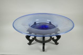 A large Murano blue glass charger, on an associated Chinese hardwood stand, 63cm diameter