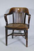 An early C20th oak office desk arm chair with shaped seat and slatted back