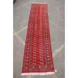 A rich red ground fine woven Bokhara runner, 98 x 364cm