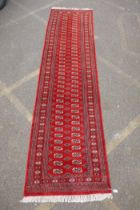 A rich red ground fine woven Bokhara runner, 98 x 364cm