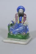 An antique Persian Qajar pottery figure of a scholar, possibly Omar Khayyam, with inscription to