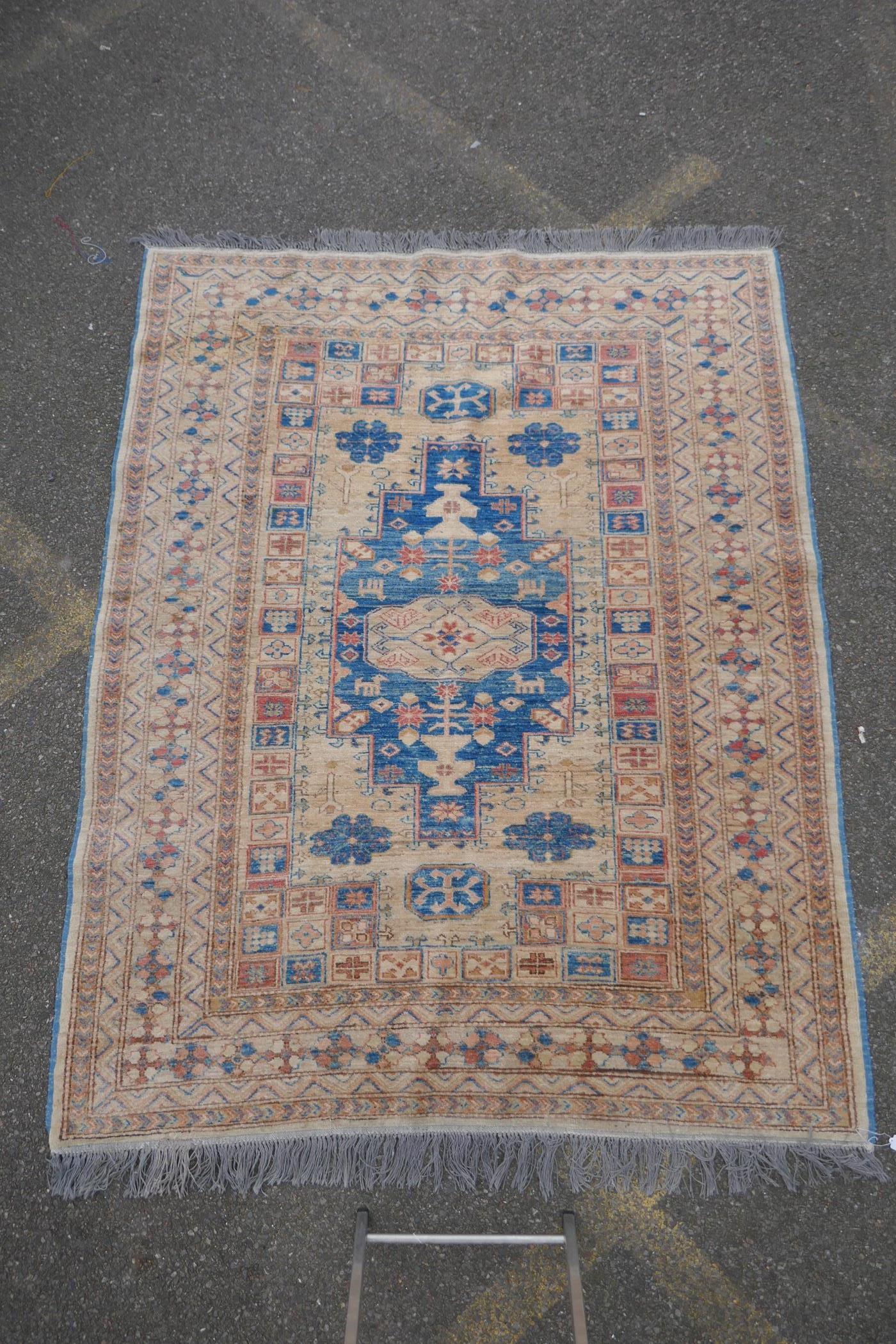 A Turkish gold ground wool rug with a blue geometric medallion design, 164 x 212cm