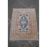 A Turkish gold ground wool rug with a blue geometric medallion design, 164 x 212cm