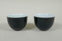 A pair of Chinese black glazed porcelain tea bowls, 4 character mark to base, 6.5cm diameter
